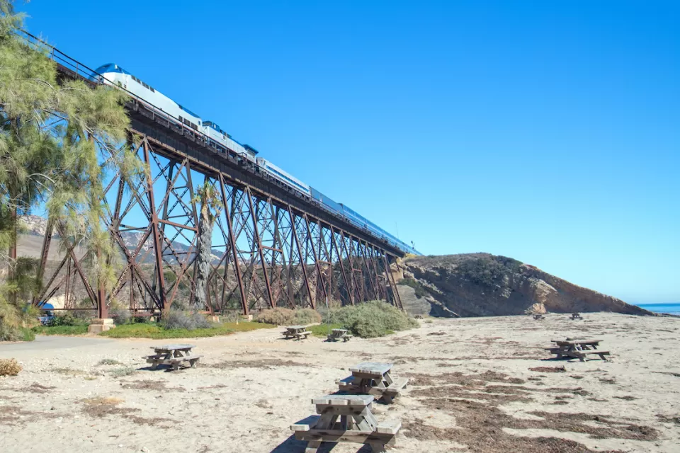 Amtrak train passing over tall trestle bridge on California coast at Gaviota Beach.